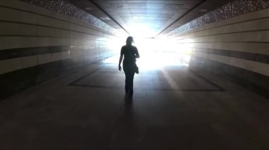 Altgeçitteki kadın silueti ışığın arka planına karşı