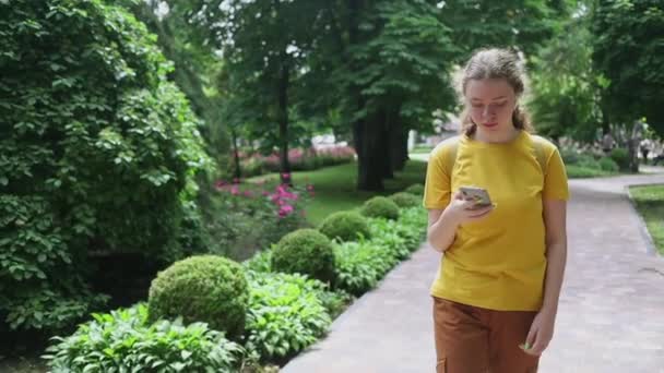 Tonårstjej Gul Shirt Med Telefon Går Längs Gränderna Stadspark — Stockvideo