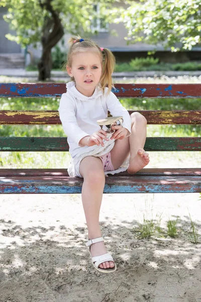 Kind schudt sandalen uit het zand — Stockfoto