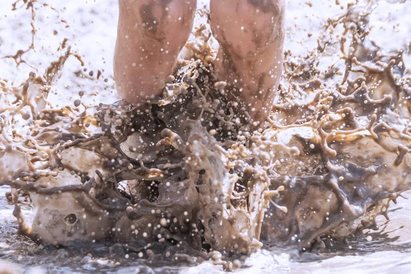 Child jumps in the mud, splashing in all directions