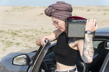 Türban daimi bir bluetooth sütun omzuna çöl arka planı olan bir araba, bir kadın portresi