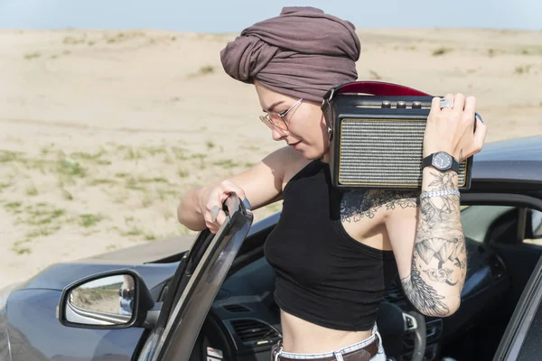 Türban daimi bir bluetooth sütun omzuna çöl arka planı olan bir araba, bir kadın portresi