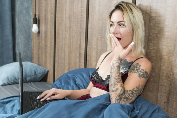 Удивлённая женщина с ноутбуком в постели — стоковое фото