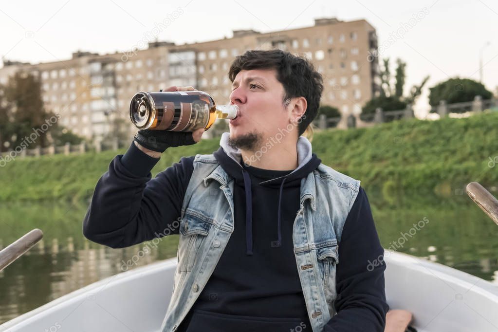 Bearded man sitting on a boat drinking rum from a bottle