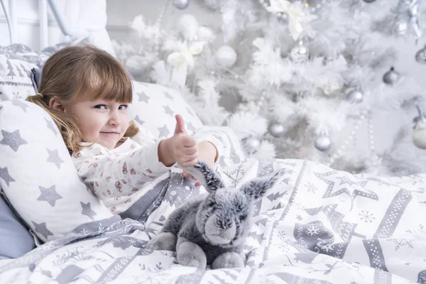 Child in bed with thumb up — Stock Photo, Image