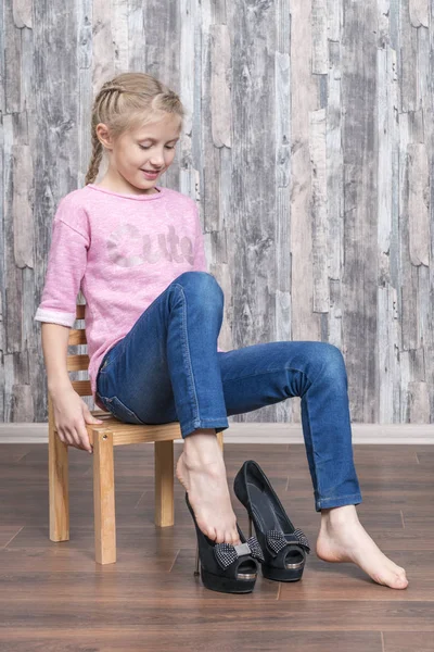 美しい少女が椅子に座るし 母親が黒かかとの高い靴を履いています — ストック写真