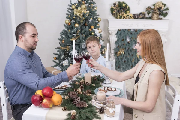 Family drinking wine sitting at a table against the background of the Christmas tree