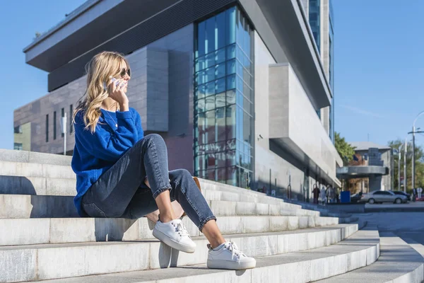 Kobieta mówi o telefon, siedząc na schodach — Zdjęcie stockowe