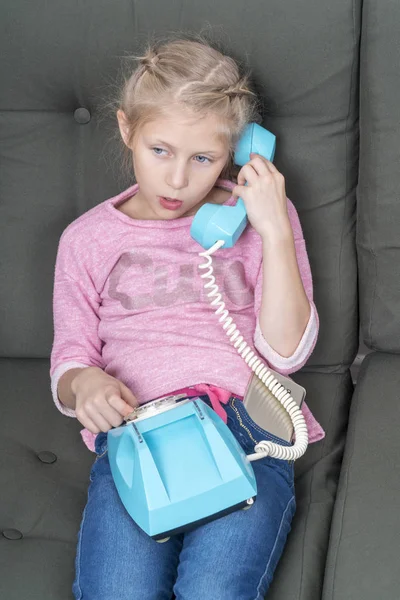 Girl is talking on blue retro phone — Stock Photo, Image