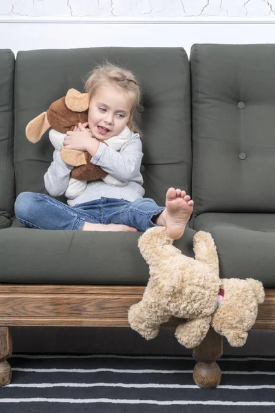 彼は足で愛されていないテディベアを押しのけて中の子抱擁彼のお気に入りのおもちゃ — ストック写真