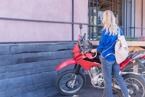 Kobieta Stoi Motocykl Czerwony Trzymając Jego Koła Jego Powrotem Kamery — Zdjęcie stockowe