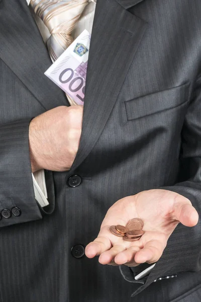 Businessman offering a trifle coins, hiding in a suit pocket a wad of money with par value of five hundred euro