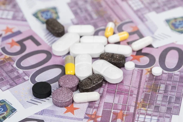 many different pills on money nominal value of five hundred euro as background