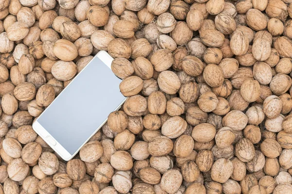 big smartphone on a pile of walnuts in the shell