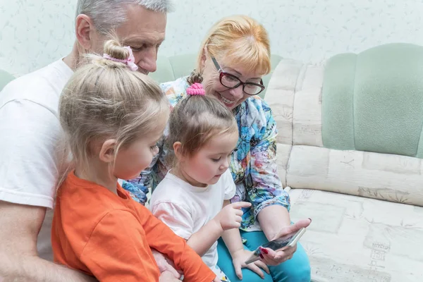 Grandparents and grandchildren look at the phone — Stock Photo, Image