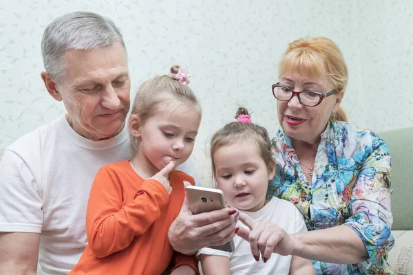 Grandmother shows smartphone to her granddaughters — Stock Photo, Image