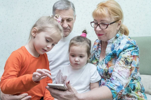 Grandchildren looking at grandmother smartphone — Stock Photo, Image