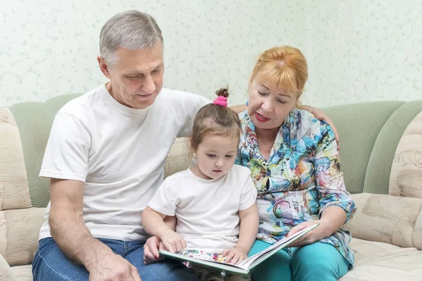 Großmutter und Großvater mit Enkelin auf der Couch — Stockfoto