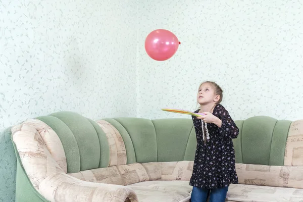 部屋のソファでラケットを使って子供のジャグリング バルーン — ストック写真