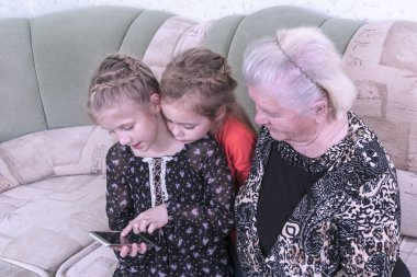 odasında kanepede otururken bir akıllı telefon kullanmak için büyük-büyükannesi granddaughters öğretmek