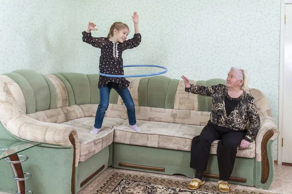 Enkelin Zeigt Großmutter Turnübungen Spinning Hoop Stehen Auf Der Couch — Stockfoto