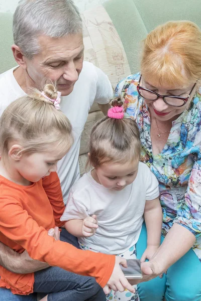 Grandchildren teach grandparents with a smartphone — Stock Photo, Image
