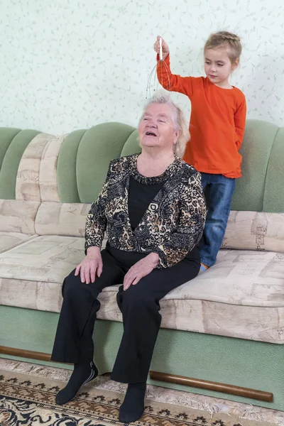 Granddaughter massages grandmother head — Stock Photo, Image