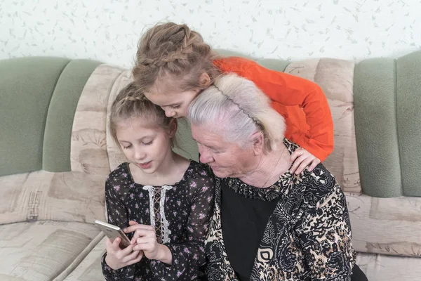 Grandchildren teach great-grandmother to use smartphone — Stock Photo, Image