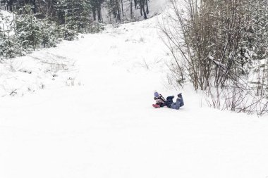 çocuklar eğlenceli düşmek topukların üzerinde bir kar tepe ile kışın
