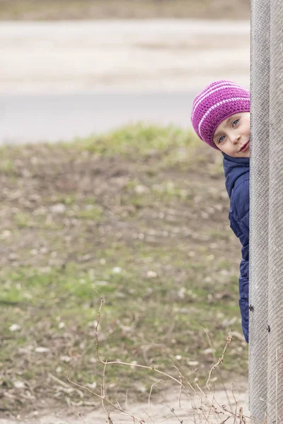 Child looks out from behind the fence — Stock Photo, Image