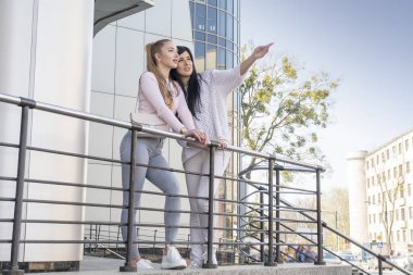 Kadın arkadaşını parmağıyla gösterir.