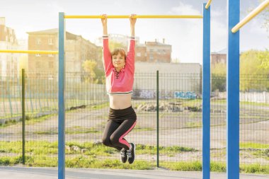 Kadın yatay çubukta asılı duruyor