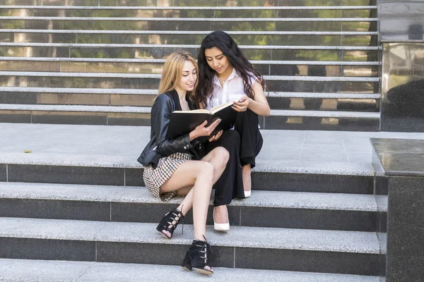 Студентки читают учебники сидя на лестнице — стоковое фото
