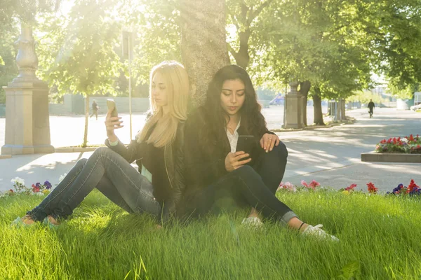 Два студента с телефонами у дерева — стоковое фото