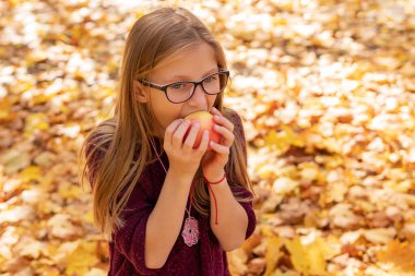 Gözlüklü kız elmayı ısırıyor.