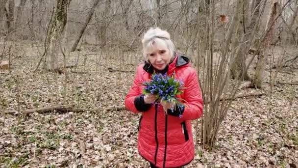 Mulher idosa está cheirando as flores — Vídeo de Stock