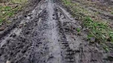 Kamera kirli kırsal bir yolda su birikintileriyle hareket ediyor.