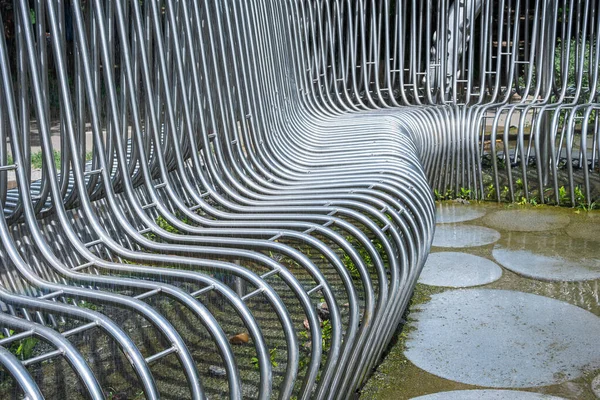 art metal bench in the pouring rain in the park, close-up