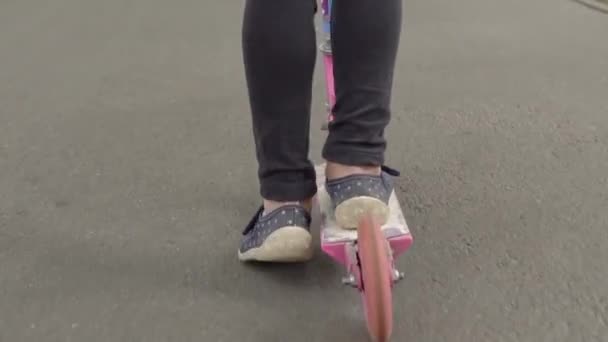 Niño montando un scooter empujando el pie — Vídeos de Stock