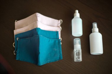 Karanlık Arkaplan 'da üç şişe dezenfektanla yüz maskeleri takan kişi, gaz, buhar, gaz ve toz gibi partikül maddeler gibi tehlikeli atmosferleri solumaktan korunuyor.
