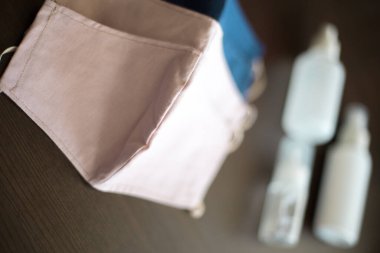 Karanlık Arkaplan 'da üç şişe dezenfektanla yüz maskeleri takan kişi, gaz, buhar, gaz ve toz gibi partikül maddeler gibi tehlikeli atmosferleri solumaktan korunuyor.