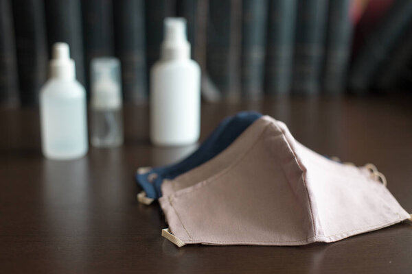 Лицевые маски на темном фоне с тремя бутылками дезинфицирующих средств Респиратор защищает владельца от вдыхания опасной атмосферы, в том числе дыма, пара, газов и твердых частиц, таких как пыль
