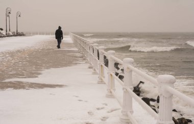 Genç adam sahilde yürüyor.
