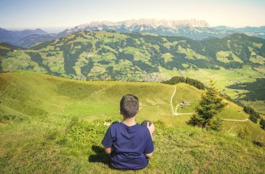 Dağın dorukından doğaya hayran genç çocuk 