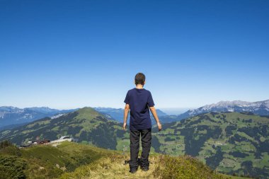 Dağın dorukından doğaya hayran genç çocuk 