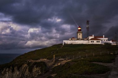 Dramatic night Portuguese landscape on the coast of Atlantic Ocean, the westernmost point of mainland Europe at Cabo da Roca. Old Lighthouse. clipart