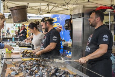 Köstence, Romanya - 20 Mayıs 2017. Festival midyesi 2017'de insanlar. Şefler Romanya'nın Eski Şehir Köstence sokaklarında ünlü Catalin Scarlatescu Chef , bir tarifi sonra midye pişirmek.