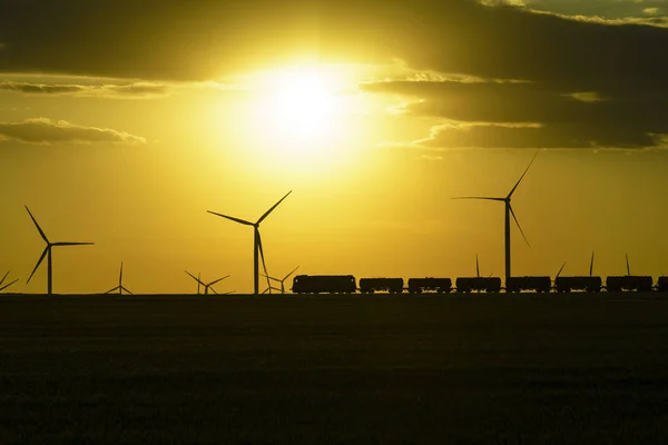 Sunset with wind turbines and train in Dobrogea , Romania