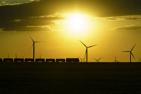 Sunset with wind turbines and train in Dobrogea , Romania