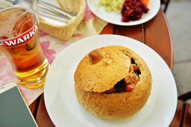 Varşova, Polonya-29 Haziran 2018. Varşova 'da Krakowskie Przedmiescie Caddesi 'nde eski kent 'in bir bistrosunda, ekmek ve eski Warka bier 'de Polonyalı domuz gulaş ile geleneksel mutfak
